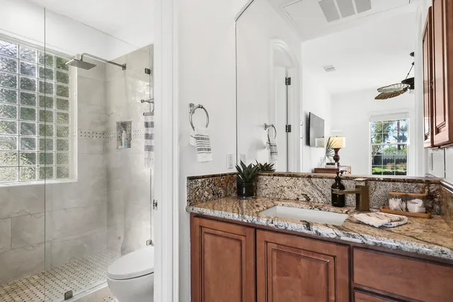 a bathroom with a granite countertop sink toilet and shower