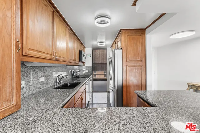 a kitchen with stainless steel appliances granite countertop a refrigerator a sink and a stove