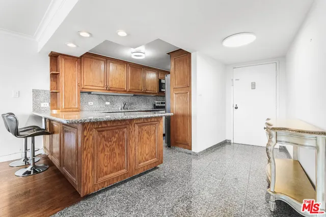 a kitchen with stainless steel appliances granite countertop a stove a sink and a refrigerator with wooden cabinets