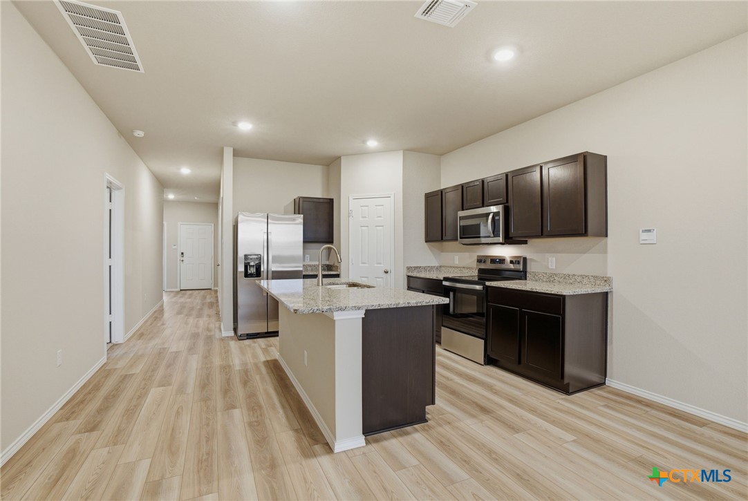 1126 Stone Vly Road, Unit B Temple, TX 76502 - Photo 8 of 26 a large kitchen with stainless steel appliances kitchen island granite countertop a stove refrigerator and a sink