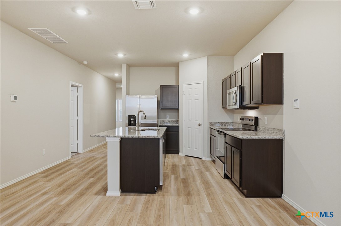 1126 Stone Vly Road, Unit B Temple, TX 76502 - Photo 10 of 26 a kitchen with stainless steel appliances a stove top oven a sink dishwasher a refrigerator and a oven with wooden floors