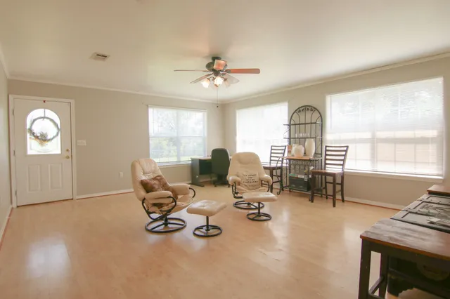 a living room with furniture hard wood floor and a floor to ceiling window