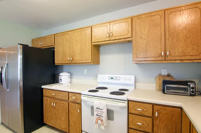 a kitchen with stainless steel appliances granite countertop a refrigerator a sink a stove and cabinets