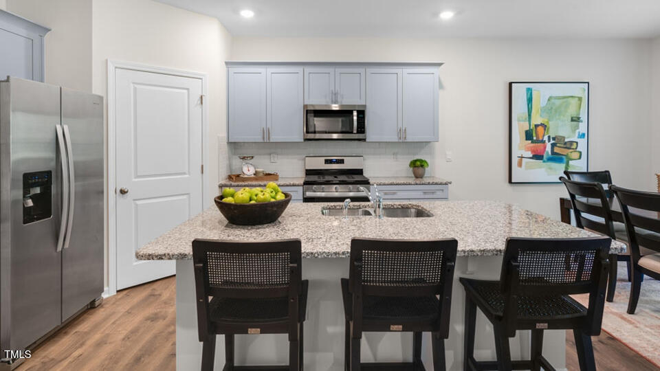 1244 Pavo Path Wendell, NC 27591 - Photo 4 of 33 a kitchen with stainless steel appliances granite countertop a dining table chairs refrigerator and microwave