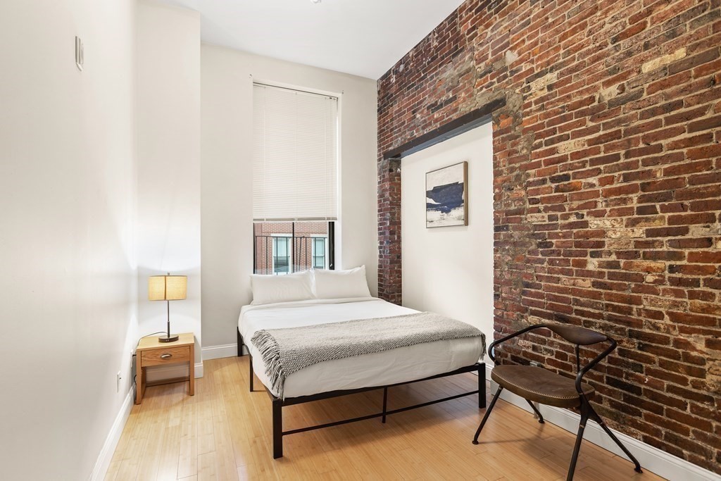 37 Temple Place, Unit 401 Boston, MA 02111 - Photo 2 of 7 a bedroom with a bed and a chair