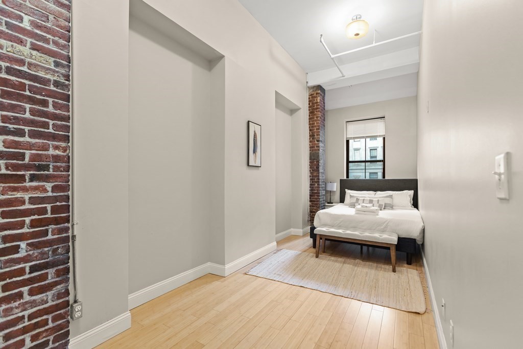 37 Temple Place, Unit 401 Boston, MA 02111 - Photo 3 of 7 a bedroom with a bed and a mirror