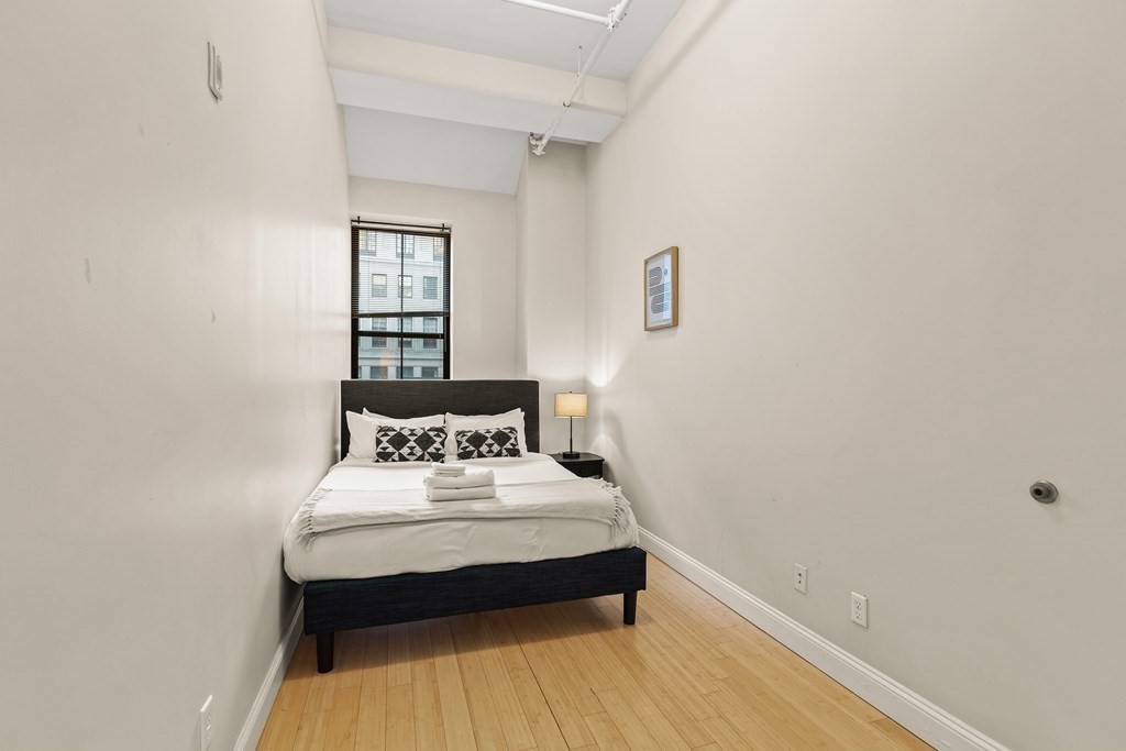 37 Temple Place, Unit 401 Boston, MA 02111 - Photo 4 of 7 a bedroom with a bed and a window