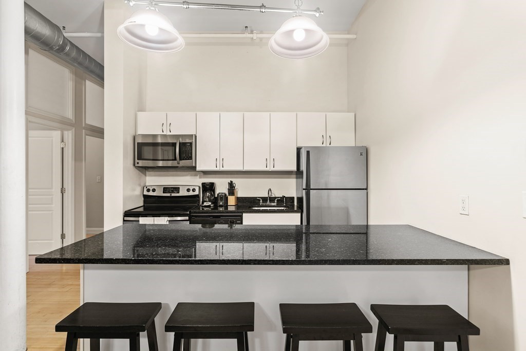 37 Temple Place, Unit 401 Boston, MA 02111 - Photo 6 of 7 a kitchen with kitchen island granite countertop a table and chairs in it