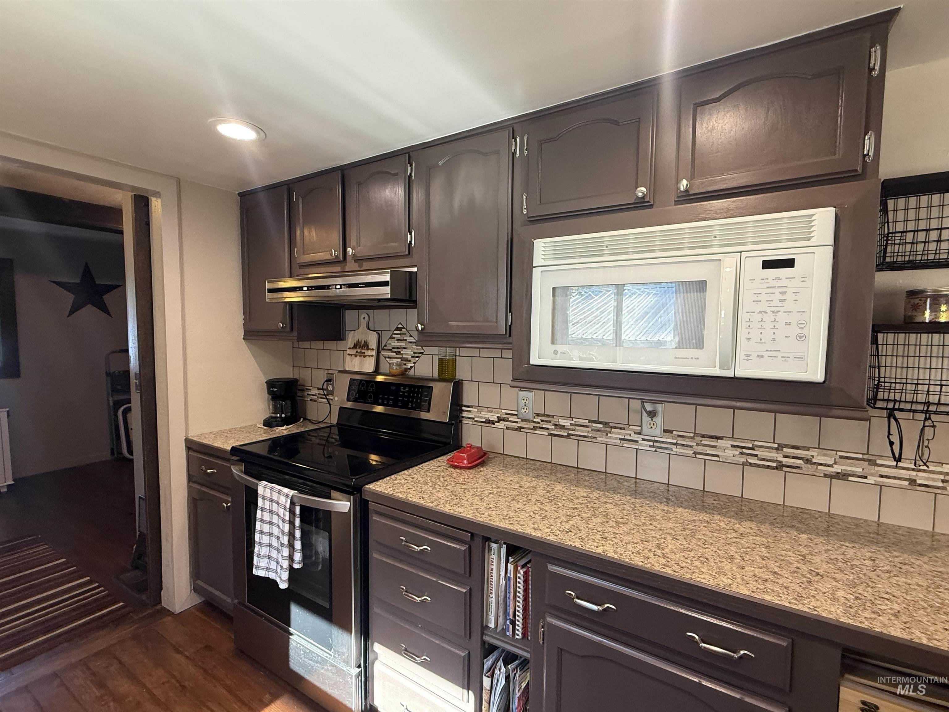 403 138th Street Orofino, ID 83544 - Photo 8 of 32 Kitchen featuring stainless steel range with electric stovetop, white microwave, under cabinet range hood, decorative backsplash, and recessed lighting