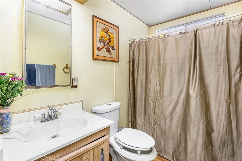 4000 Pierce Street, Unit 106 Riverside, CA 92505 - Photo 13 of 18 a bathroom with a sink a toilet and shower curtain