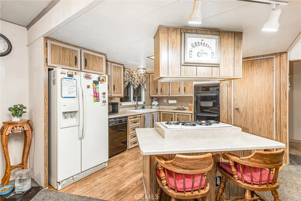 4000 Pierce Street, Unit 106 Riverside, CA 92505 - Photo 5 of 18 a kitchen with stainless steel appliances granite countertop a refrigerator a stove a sink dishwasher and a dining table with wooden floor
