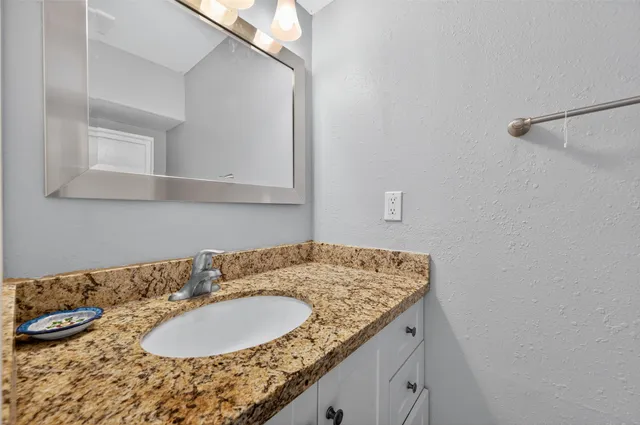 a bathroom with a granite countertop sink and a mirror
