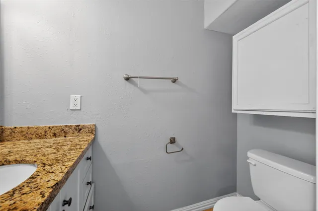 a bathroom with a granite countertop toilet and a sink
