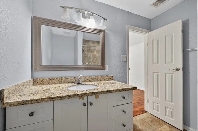 a bathroom with a granite countertop sink and a mirror