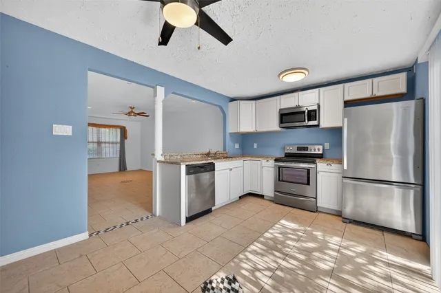 a kitchen with granite countertop a refrigerator and a stove top oven