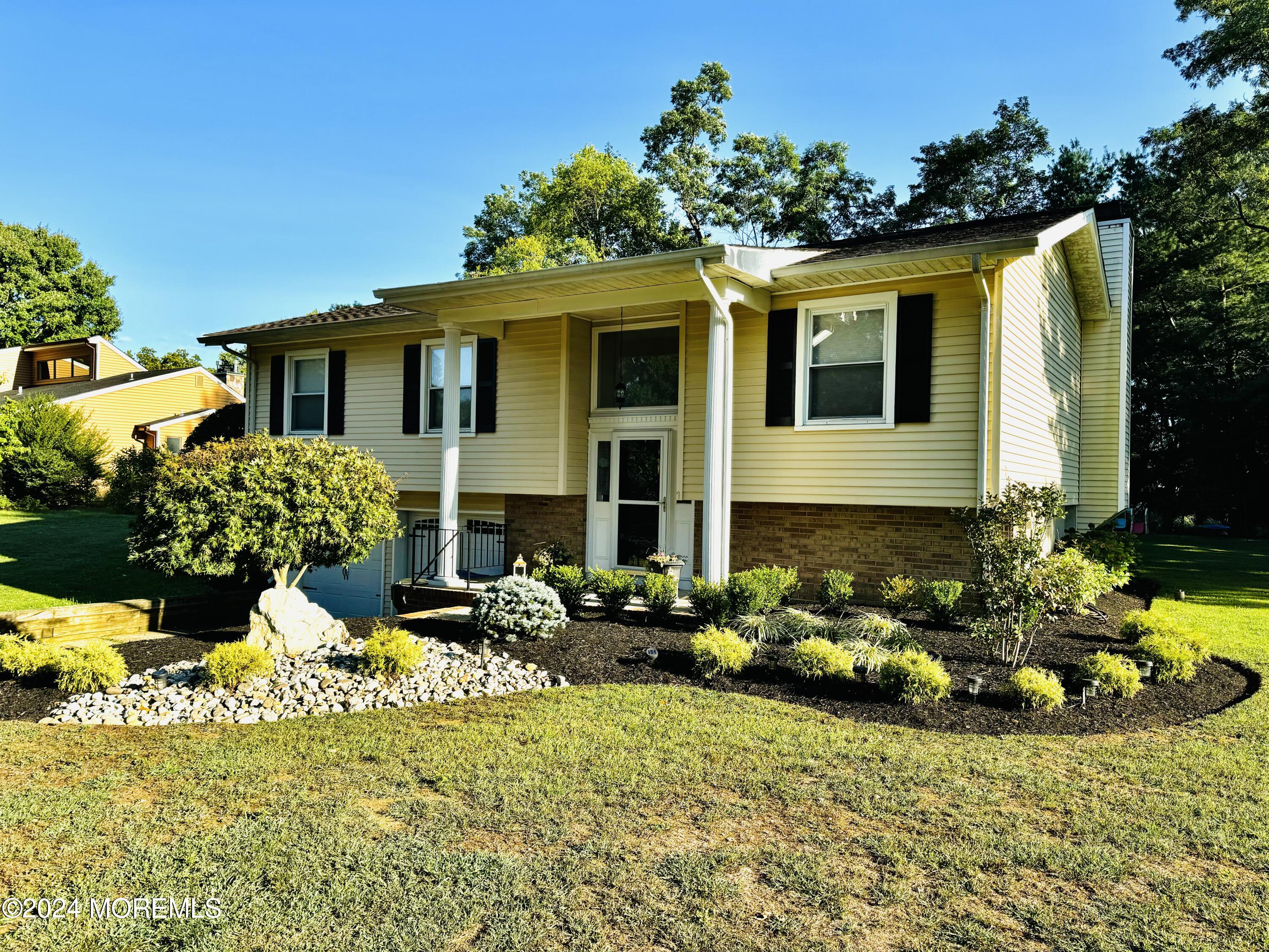 8 Old Farm Road Tinton Falls, NJ 07724 - Photo 2 of 24 a front view of a house with lots of flowers around