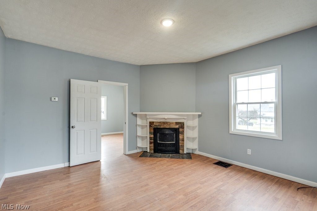 1607 9th Street Southwest Canton, OH 44706 - Photo 8 of 41 Living area featuring wood-finish flooring, a corner fireplace with stone surround and white mantel, and a multi-pane window