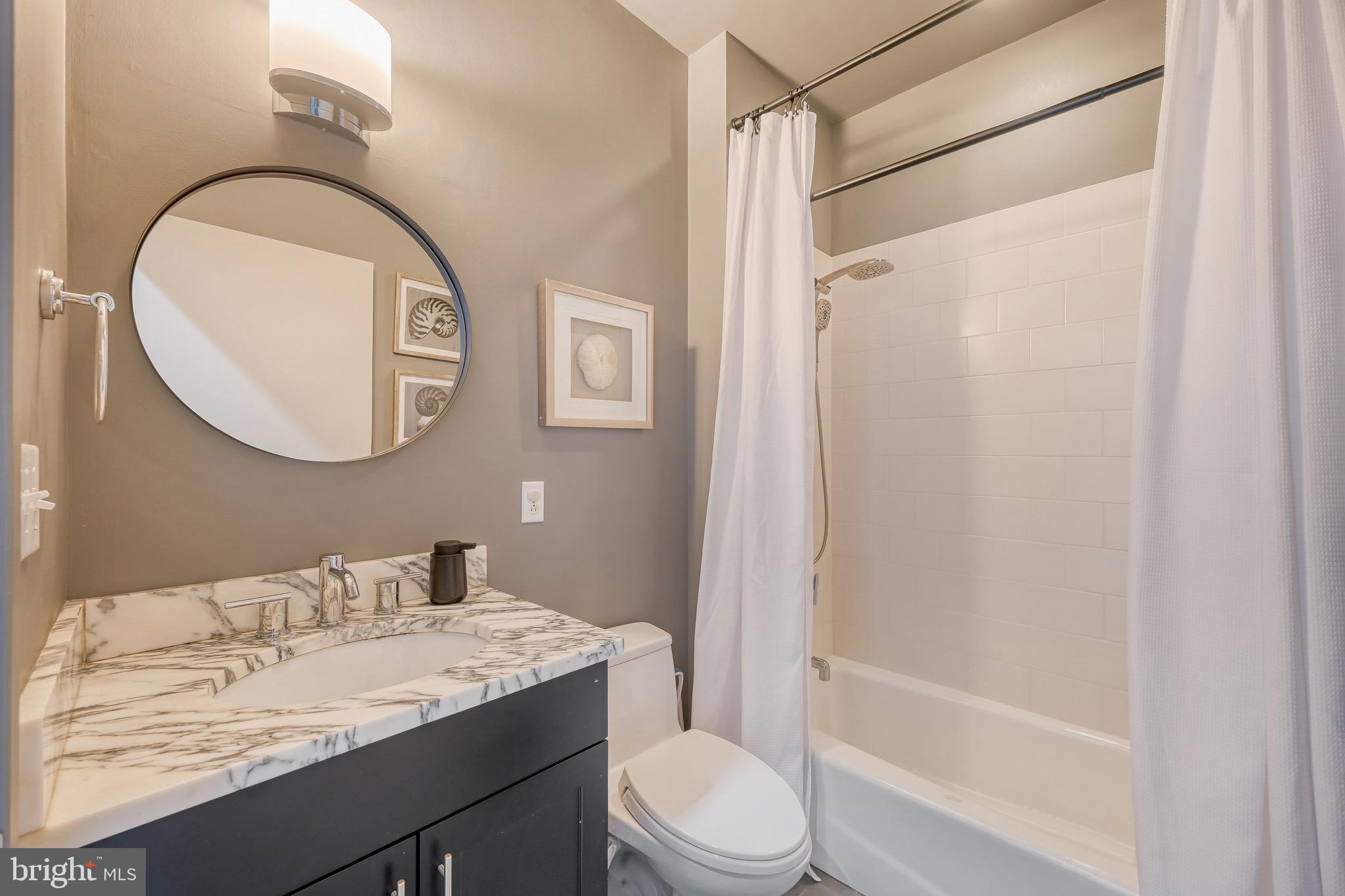 1200 Steuart Street, Unit 713 Baltimore, MD 21230 - Photo 18 of 43 a bathroom with a granite countertop sink toilet a mirror and shower