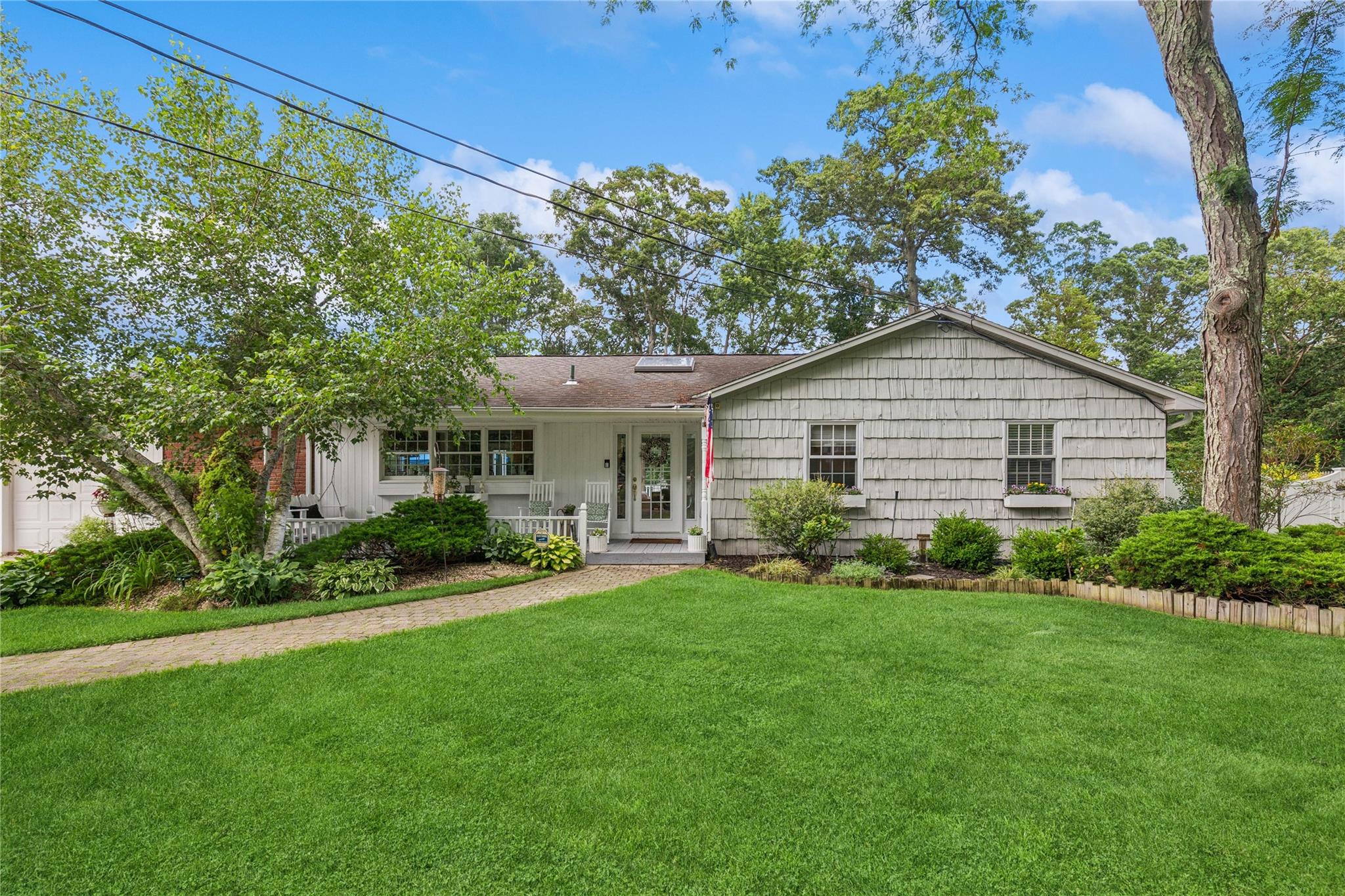 Ranch-style house with a front yard, a porch, and a shingled roof