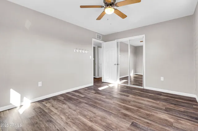 a view of empty room with wooden floor and fan