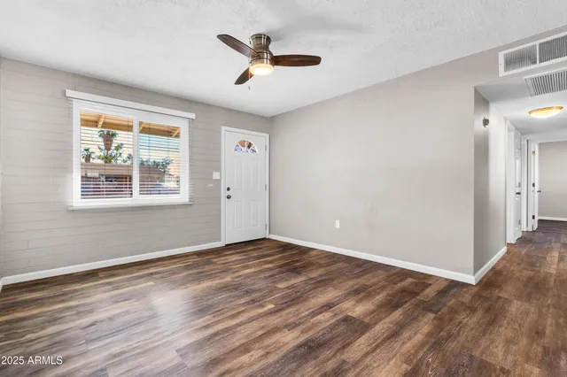 a view of an empty room with wooden floor and a window