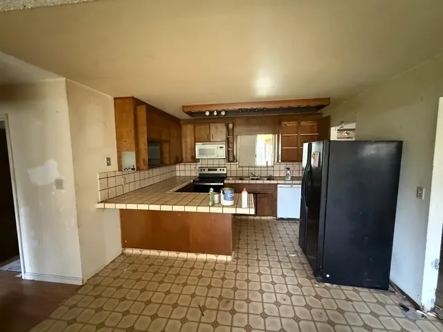 a view of a kitchen with kitchen island granite countertop a refrigerator and a counter top space