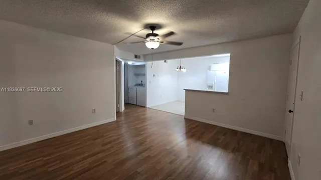 an empty room with wooden floor chandelier fan and entryway