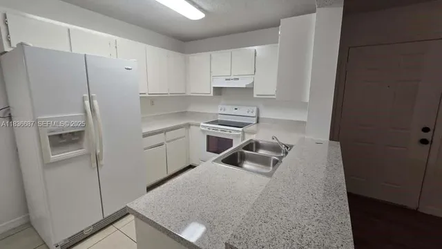a kitchen with white cabinets and refrigerator