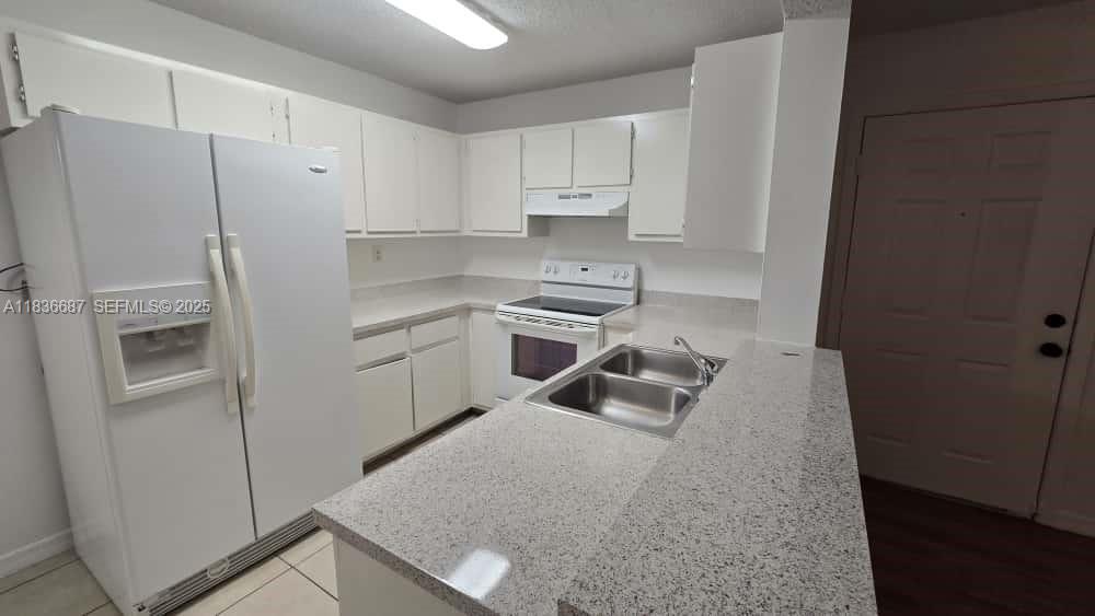 301 Palm Way, Unit 205 Pembroke Pines, FL 33025 - Photo 7 of 23 a kitchen with white cabinets and refrigerator
