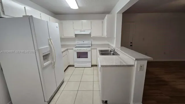 a kitchen with a refrigerator sink and cabinets