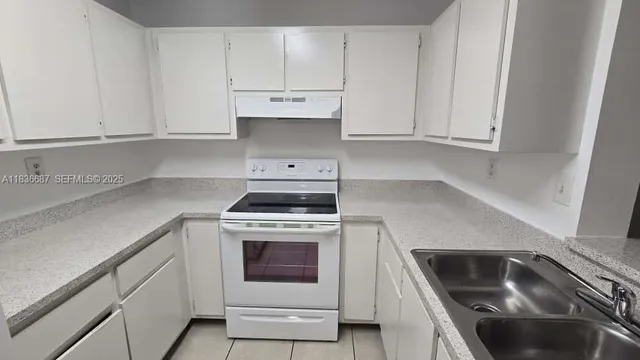 a kitchen with granite countertop white cabinets and a stove