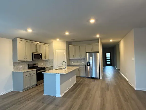 a kitchen with stainless steel appliances kitchen island granite countertop a stove refrigerator and a sink