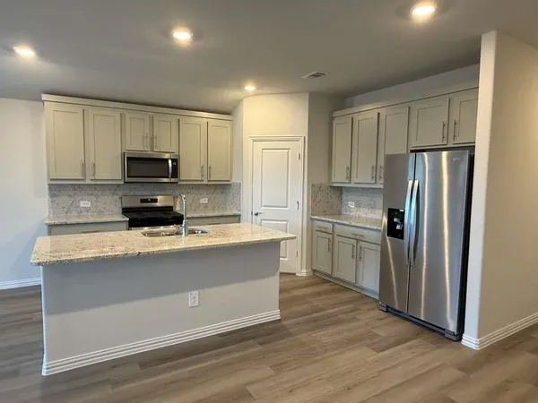 a large kitchen with stainless steel appliances a refrigerator and a stove top oven