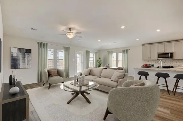 a living room with furniture kitchen view and a large window