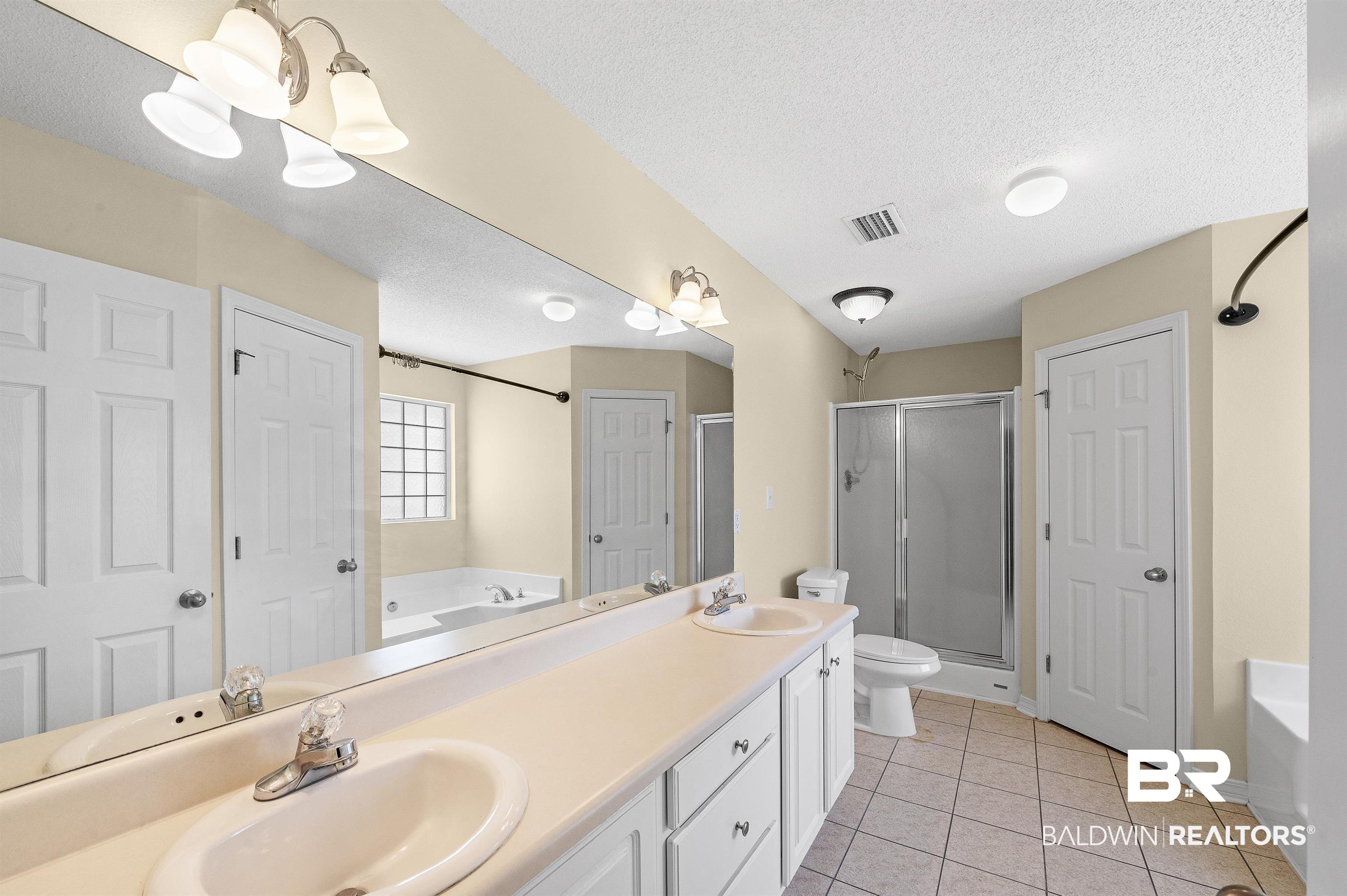 12443 Venice Boulevard Foley, AL 36535 - Photo 44 of 59 Full bathroom featuring separate shower and tub, toilet, a textured ceiling, and vanity