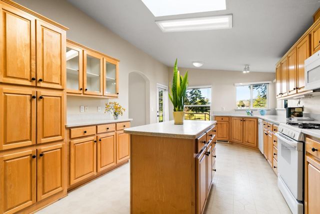 a kitchen with stainless steel appliances granite countertop a refrigerator a sink dishwasher a stove and white countertops with wooden floor