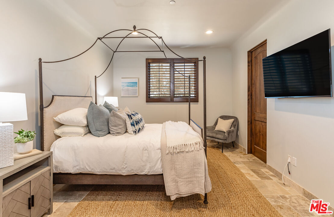 4800 Latigo Canyon Road Malibu, CA 90265 - Photo 23 of 56 a bedroom with a bed a rug and a flat tv screen on the dresser