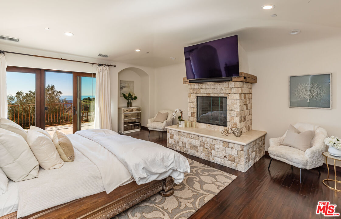 4800 Latigo Canyon Road Malibu, CA 90265 - Photo 26 of 56 a bedroom with furniture a fireplace and a flat screen tv