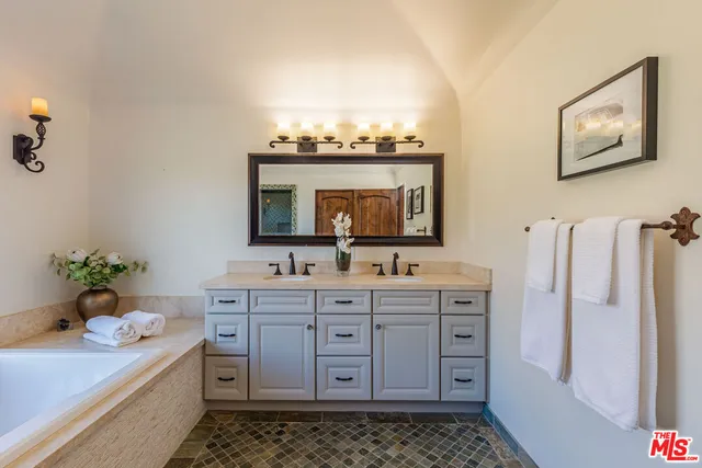 a bathroom with a granite countertop sink a mirror and shower