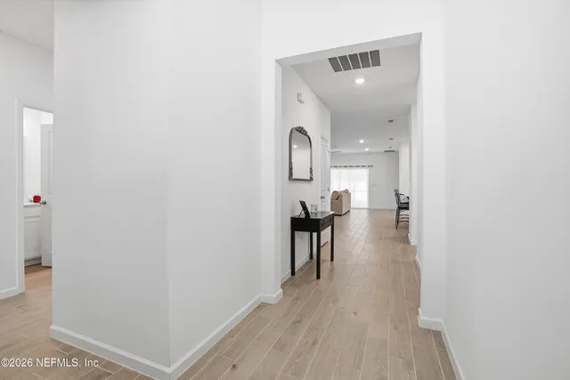 a view of a hallway with wooden floor and a bathroom