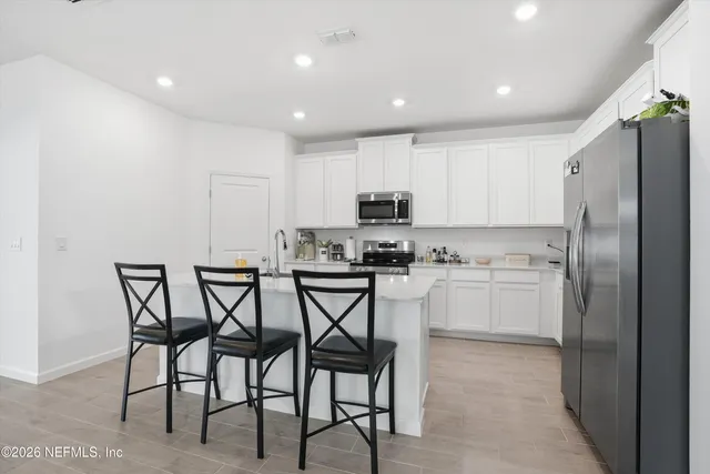 a kitchen with a table chairs refrigerator and microwave