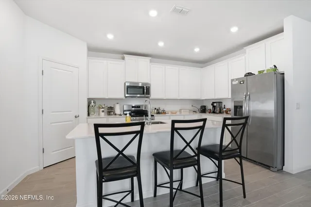 a kitchen with stainless steel appliances a table chairs refrigerator and microwave