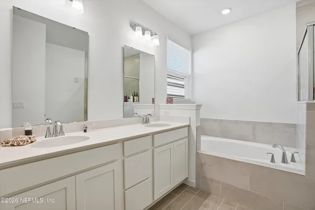 a bathroom with a sink double vanity granite tub and a mirror