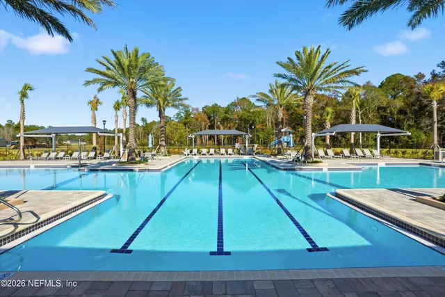 a small pool with lawn chairs under an umbrella