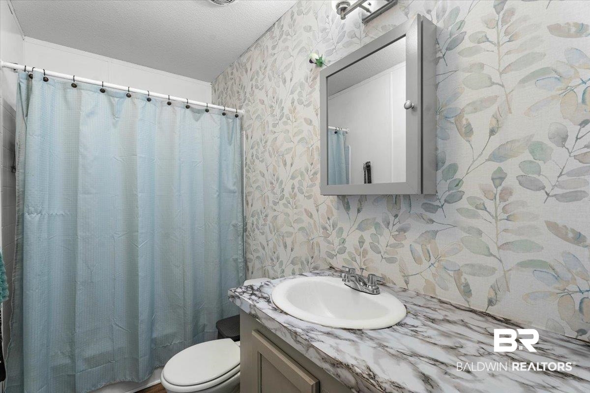 21011 River Road Robertsdale, AL 36567 - Photo 17 of 29 Bathroom featuring a vanity with a white oval sink and a patterned countertop