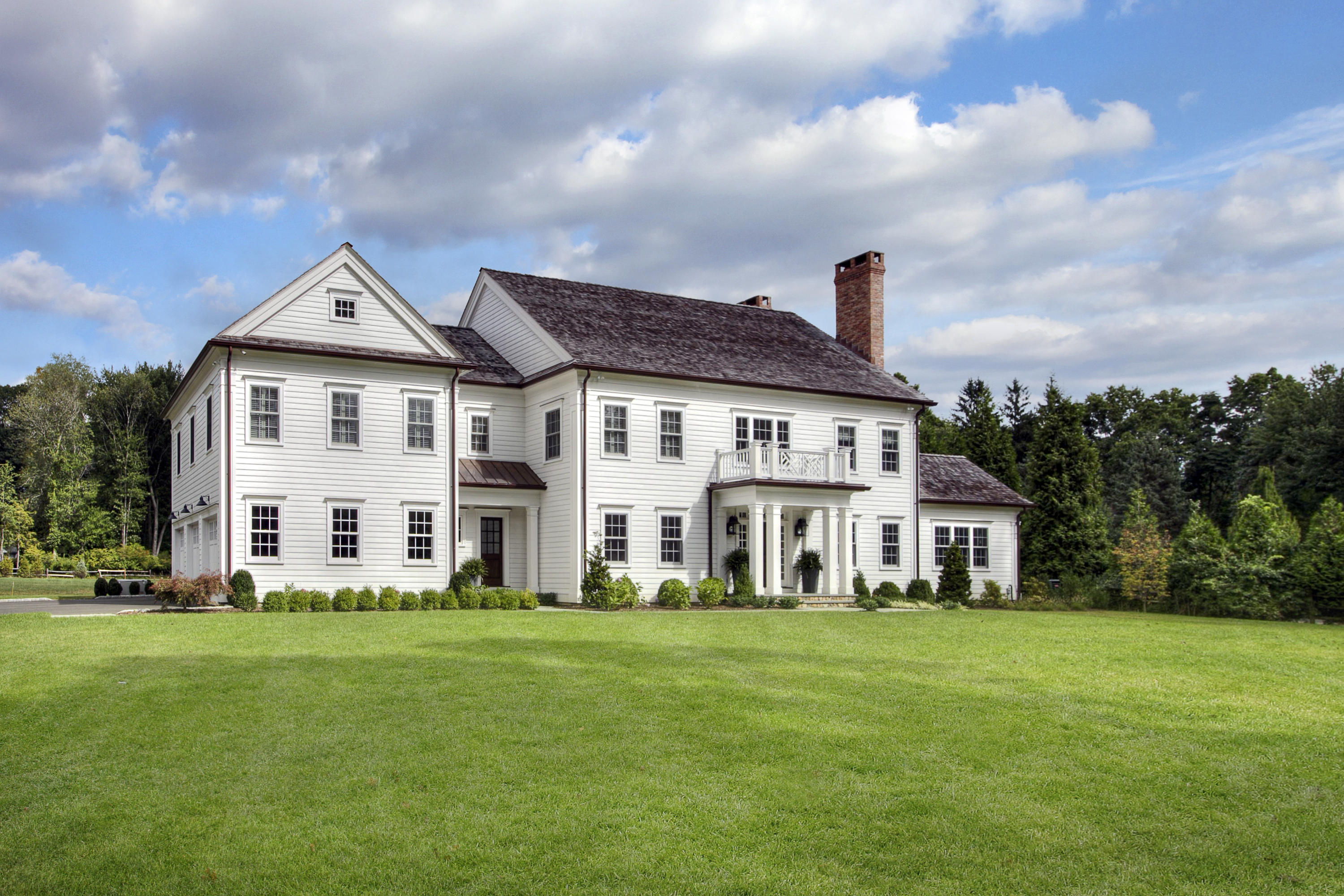 a front view of a house with a garden and trees