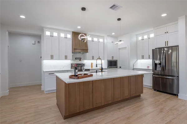 a kitchen with stainless steel appliances granite countertop a sink a stove a refrigerator and island with wooden floor