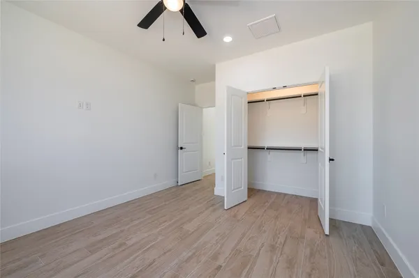 an empty room with wooden floor and a ceiling fan