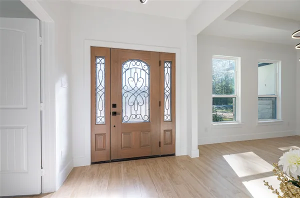 an empty room with wooden floor mirror and windows