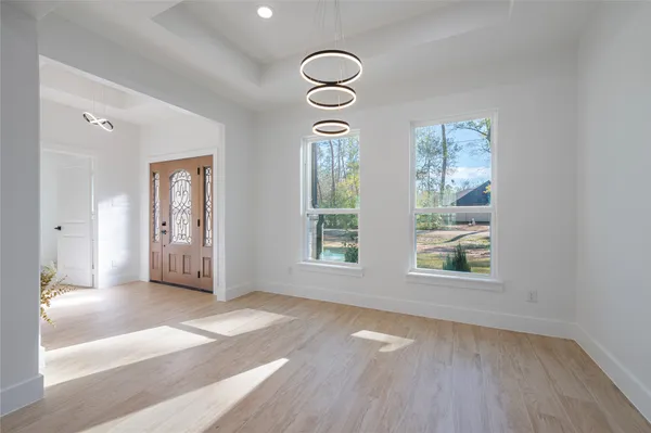 an empty room with wooden floor mirror and windows